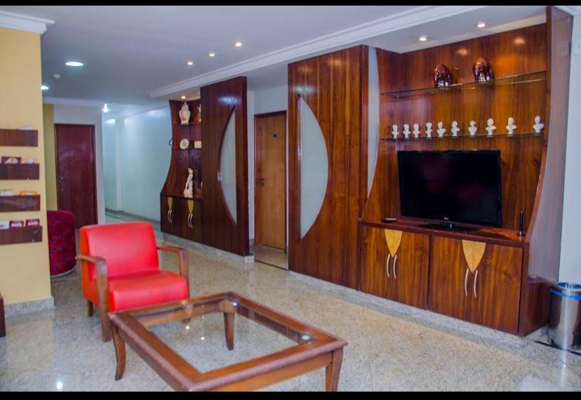 a living room with a red chair and a television at Crystal Plaza Hotel Marista in Goiânia
