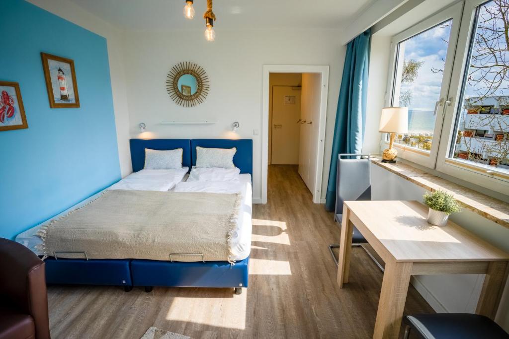 ein blaues Schlafzimmer mit einem Bett und einem Tisch in der Unterkunft Studio 31 "Strandgut" in Grömitz