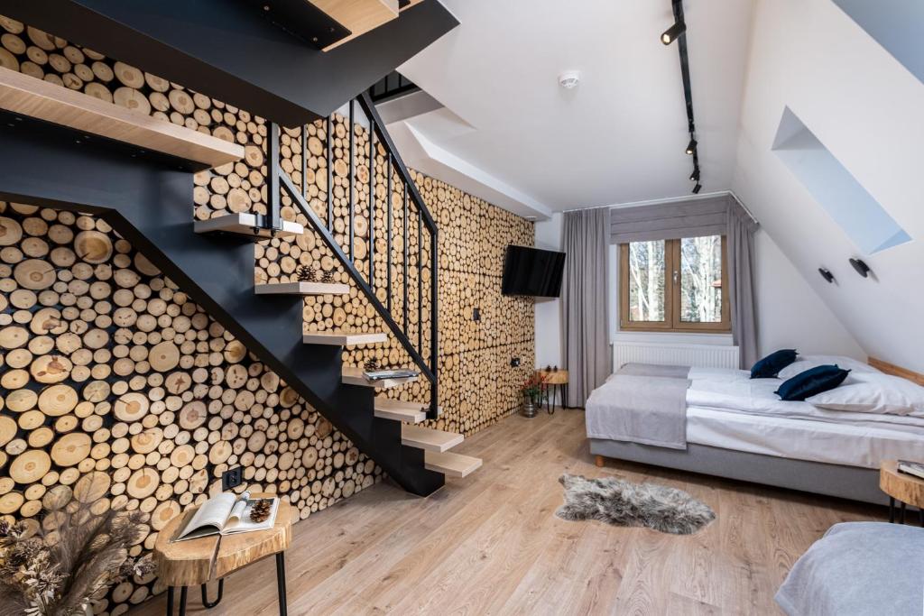 a bedroom with a logs wall and a bed and stairs at Villa 7 Folk & Modern in Zakopane