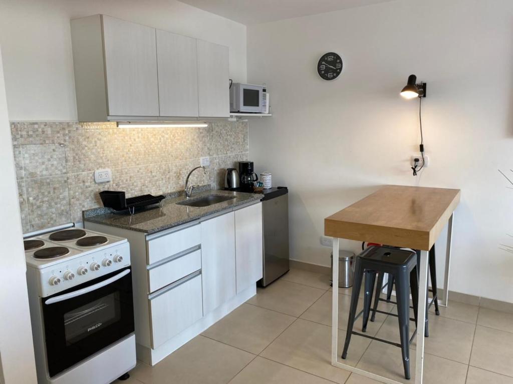 uma cozinha com armários brancos, um fogão e uma mesa em Penguins Flats 3 em Ushuaia