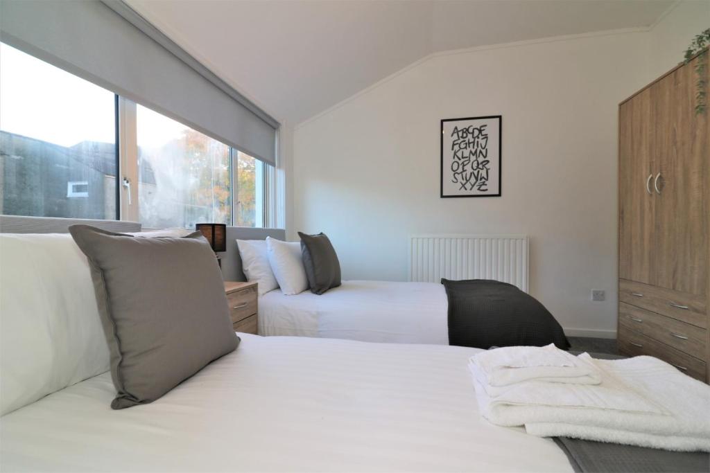 a bedroom with two beds and a large window at Signature - Alder View in Cumbernauld