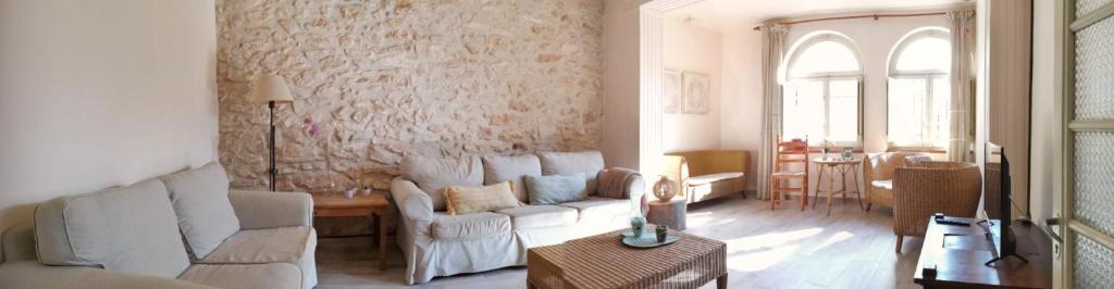 una sala de estar con muebles blancos y una pared de piedra. en Les violetes, en Serra de Almós