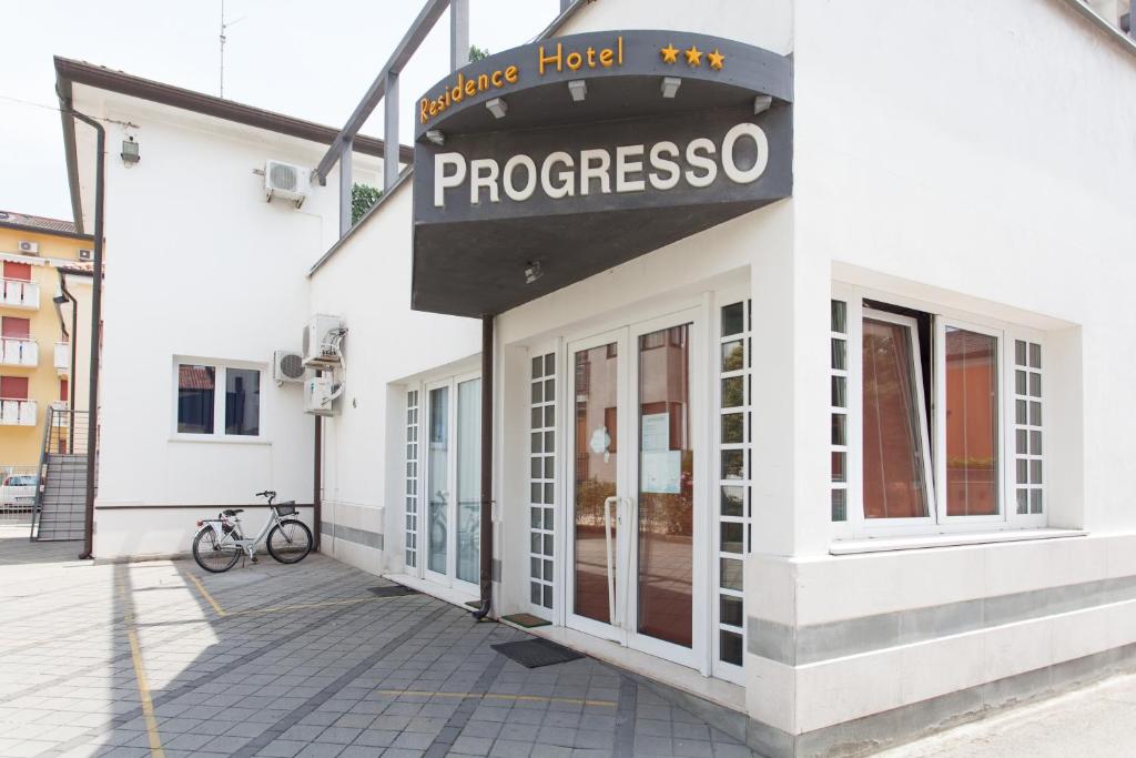 a white building with a sign that reads progresso at Hotel & Residence Progresso in Lido di Jesolo