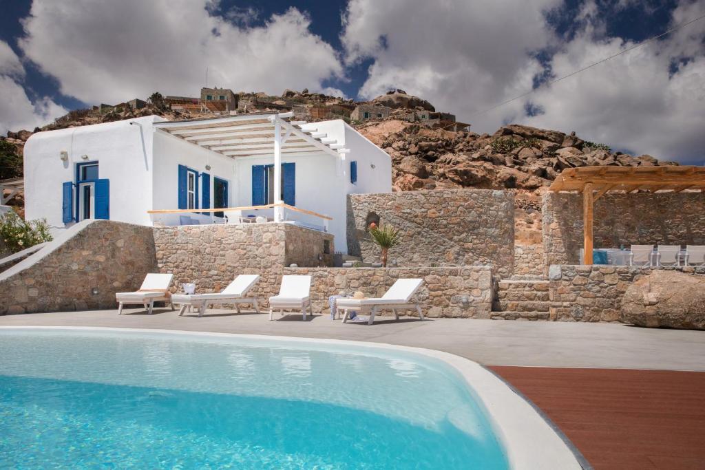 - une piscine avec des chaises et une maison dans l'établissement VENUS VIEW, à Kalafatis