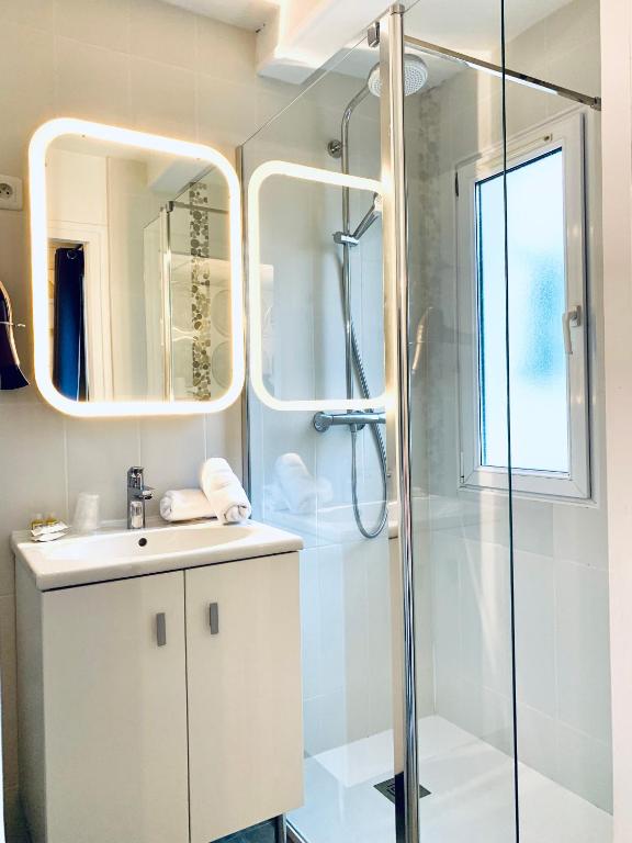 a bathroom with a shower and a sink and a mirror at Hôtel Gaspard in Le Touquet-Paris-Plage