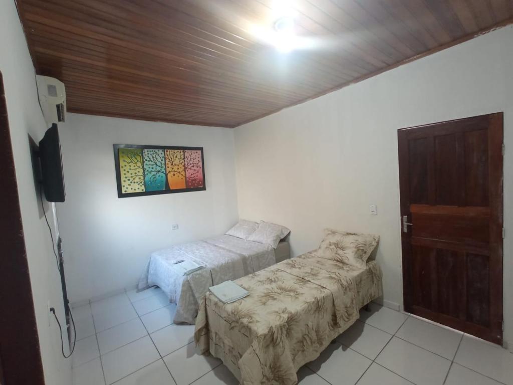 a bedroom with two beds and a tv in it at Suíte agradável no centro da cidade. in Boa Vista