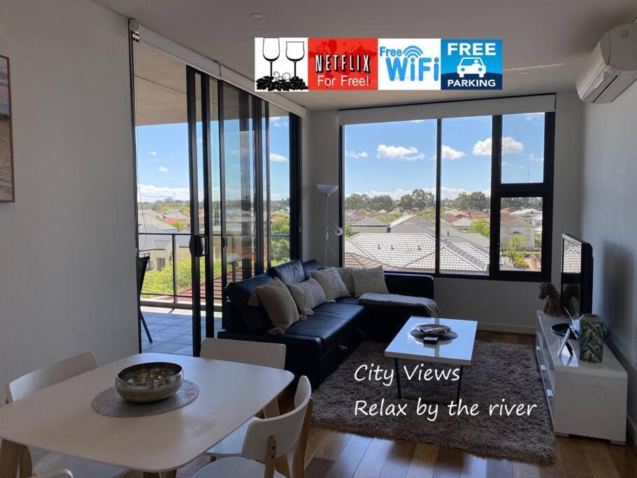 uma sala de estar com um sofá e uma mesa em BEAUTIFUL CITY VIEWS CLOSE CITY AIRPORT FREE WINE em Perth