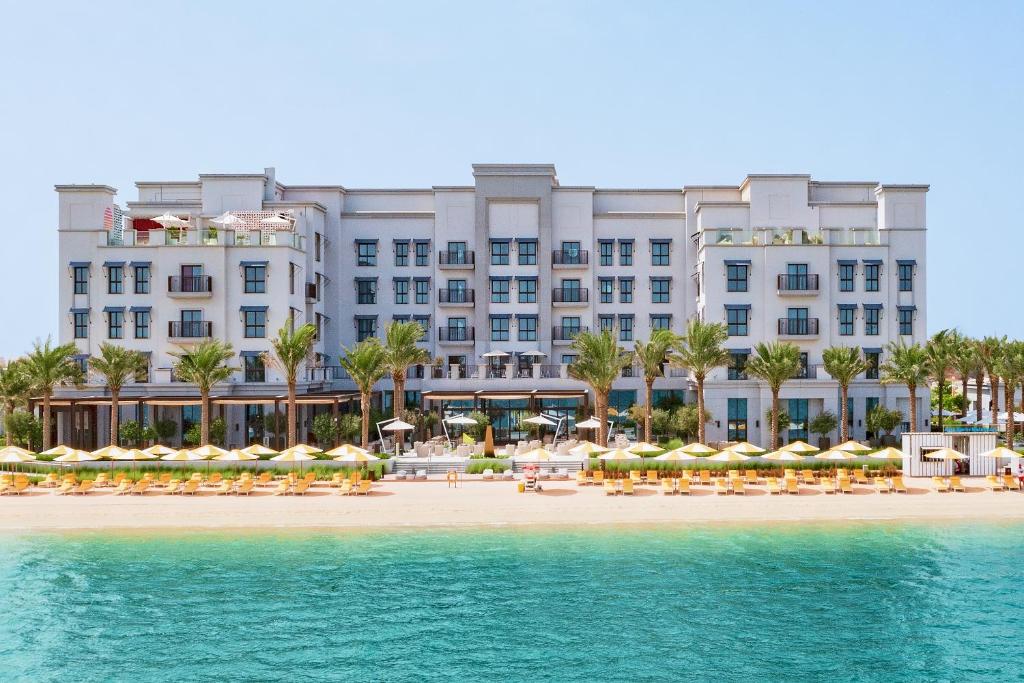 a hotel on the beach with chairs and umbrellas at Vida Beach Resort Umm Al Quwain in Umm Al Quwain