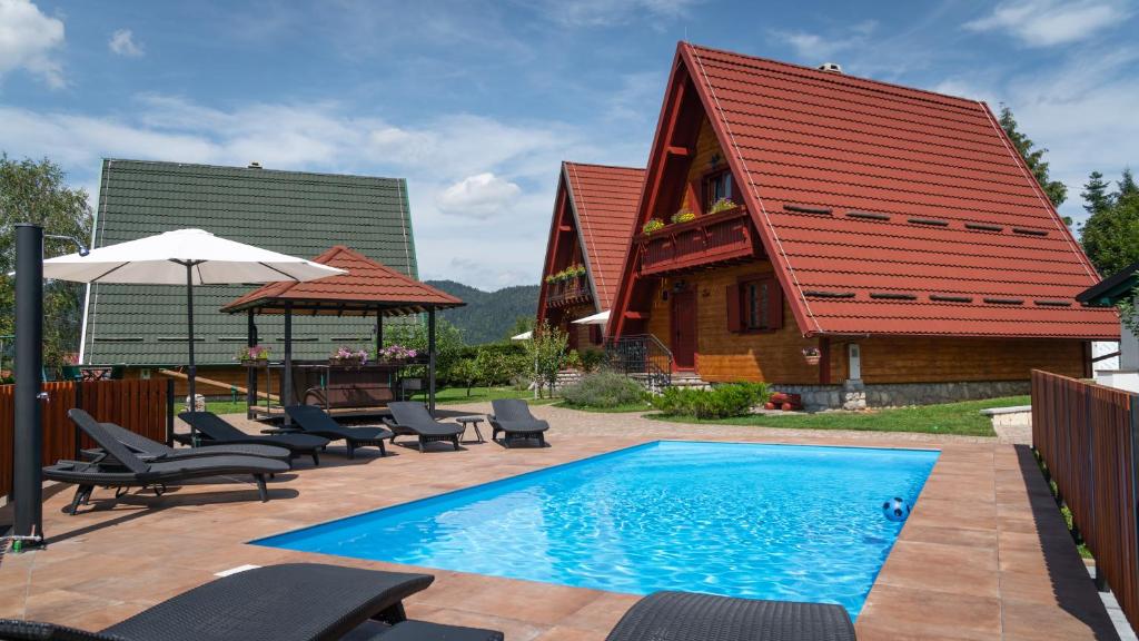 a swimming pool with chairs and a house at Chalets Runolist in Crni Lug