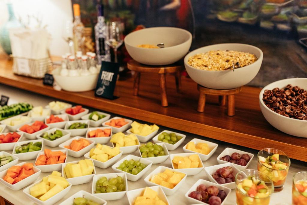 A breakfast buffet with cut fruit, cereals and small fruit desserts.