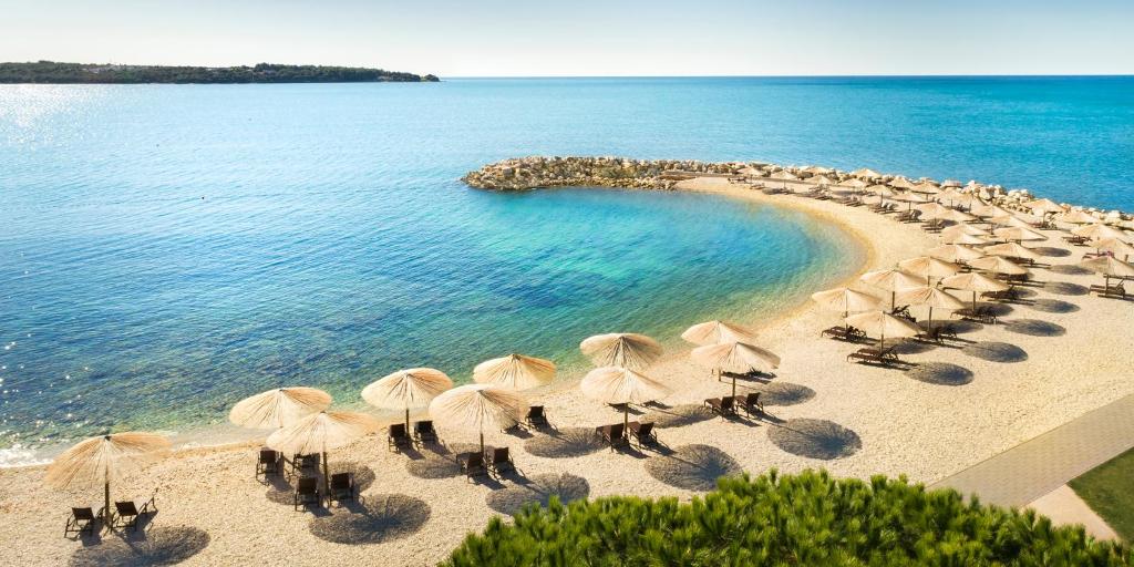a group of umbrellas and chairs on a beach at Aminess Vival Maestral Hotel in Novigrad Istria