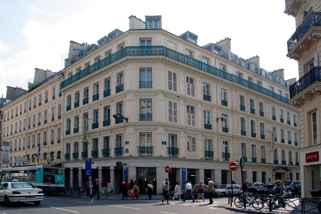 un gran edificio blanco con gente caminando delante de él en HOTEL DU PRINTEMPS en París