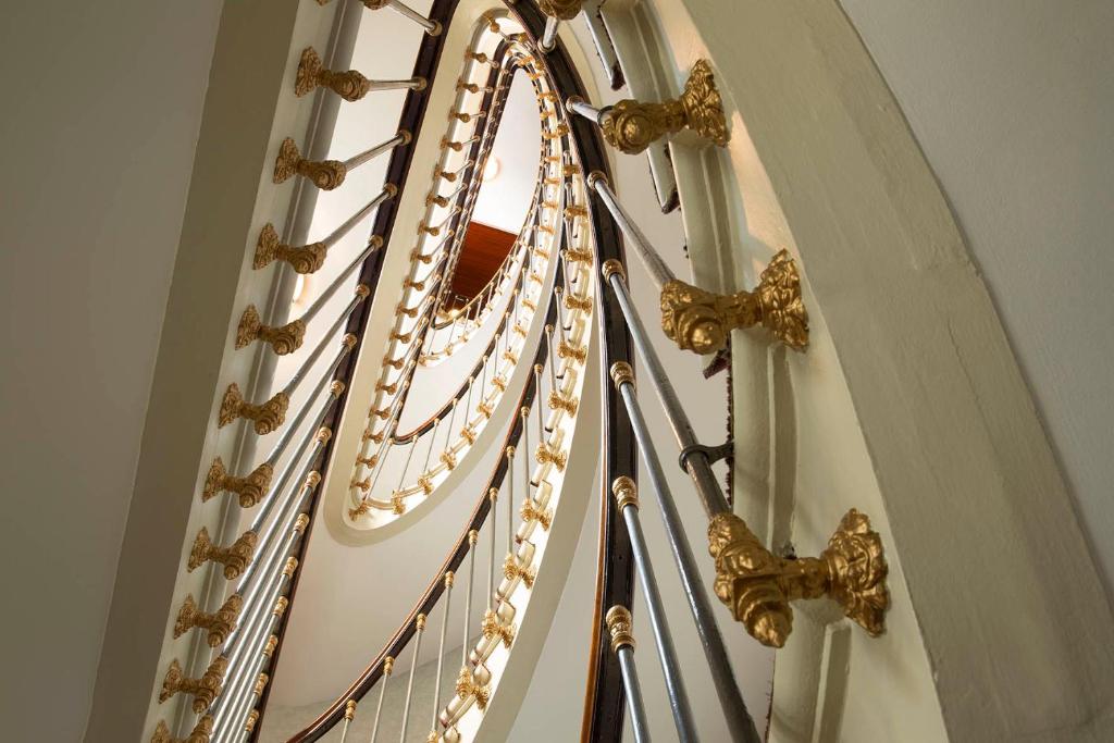 a close up of a spiral staircase with golditures at HOTEL DU PRINTEMPS in Paris