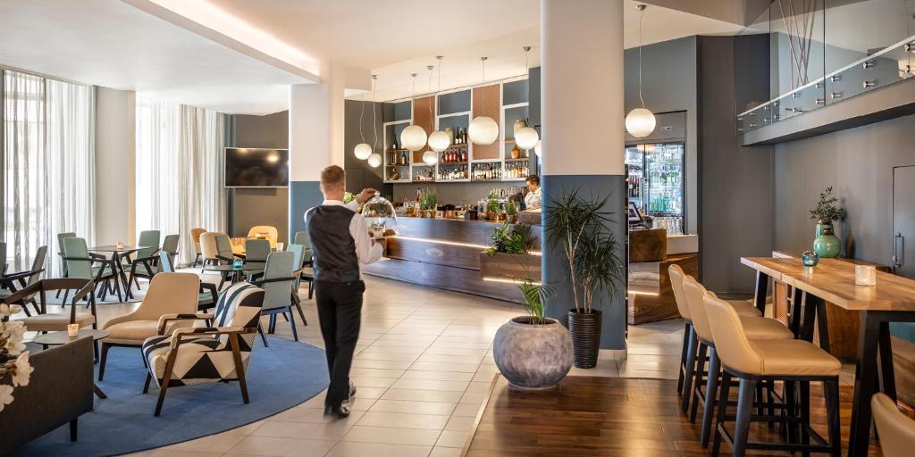 a man in a suit walking through a restaurant at Aminess Vival Maestral Hotel in Novigrad Istria