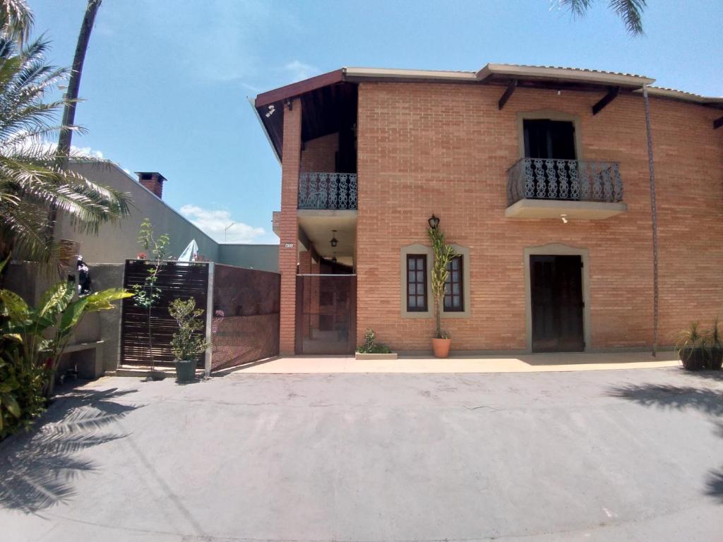 a brick house with a balcony and a driveway at Sobrado com piscina em condomíno fechado a 150 M da praia in Caraguatatuba