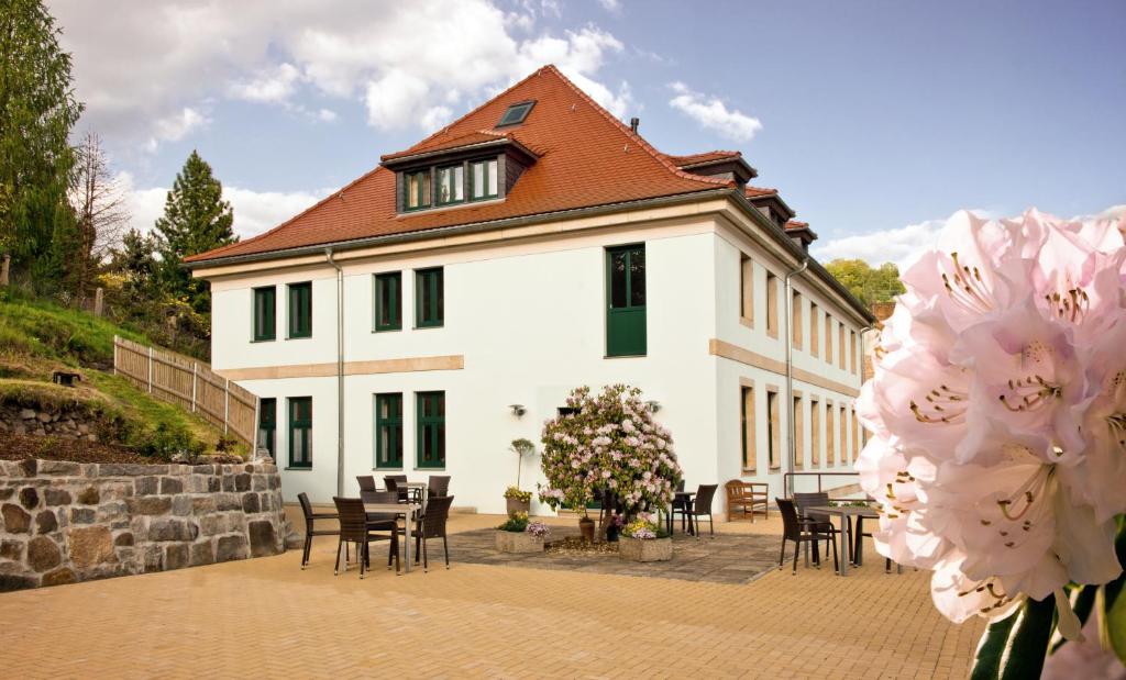a white building with tables and chairs in front of it at Pension Am Finkenberg in Sebnitz