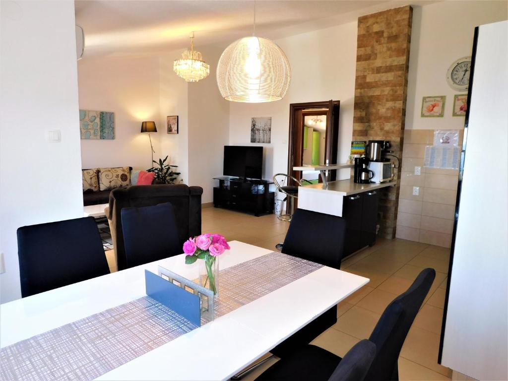 a dining room and living room with a table and chairs at Apartman "Sabine" with pool in Omišalj