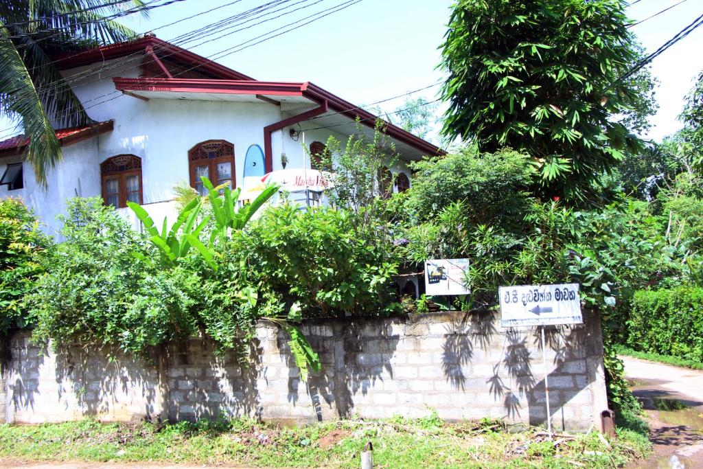 una casa blanca con un cartel delante en Malsha Villa, en Weligama