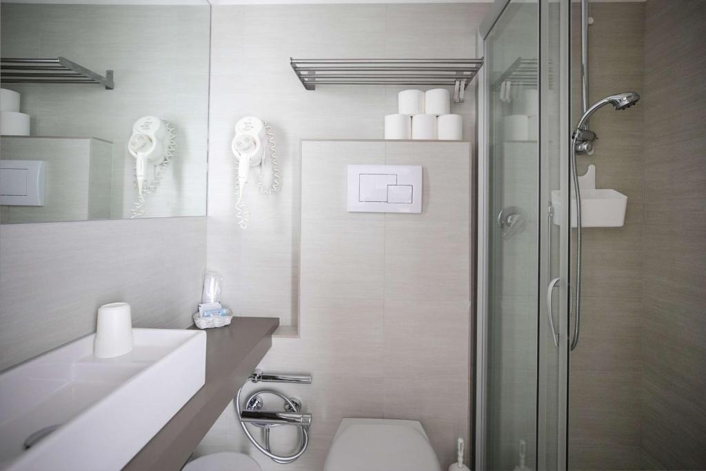 uma casa de banho com um chuveiro, um WC e um lavatório. em Hotel Benvenuto em Caorle