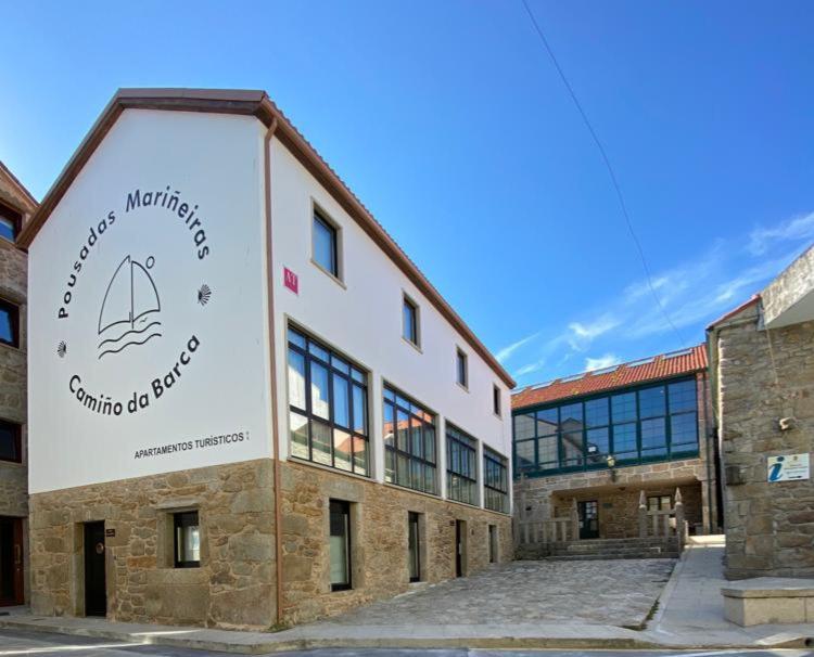 um edifício com um sinal na lateral em Pousadas Mariñeiras,sl - AT "Camiño da Barca" em Muxía