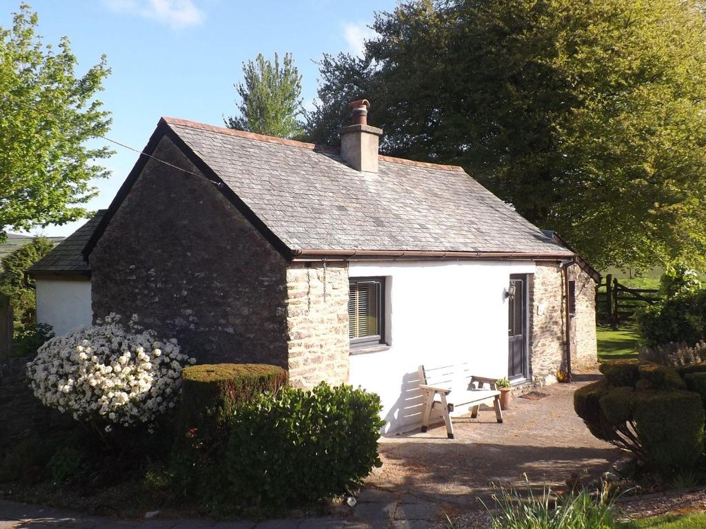 a small stone cottage with a bench in front of it at Beech Cottage in Ilfracombe