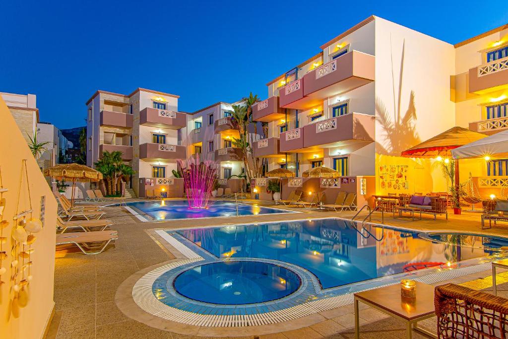 un hôtel avec une piscine en face d'un bâtiment dans l'établissement Ilios Malia Hotel Resort, à Mália