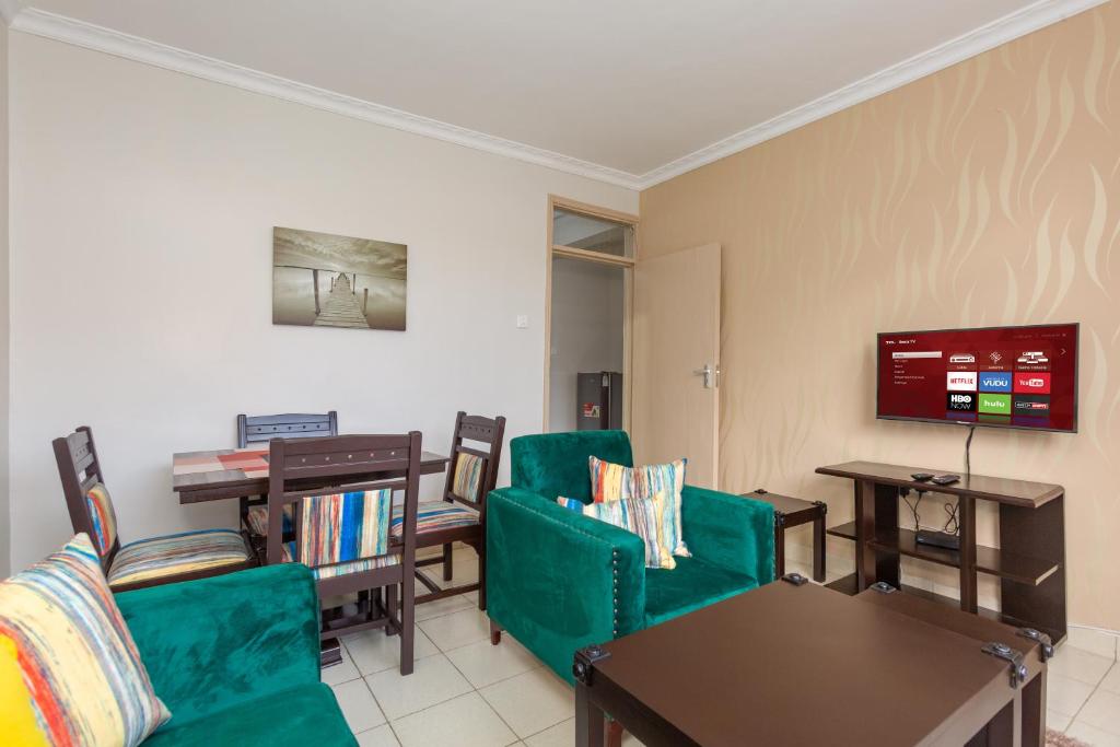 a living room with green chairs and a tv at Fully furnished 1-bedroom Apartment in Eldoret in Eldoret
