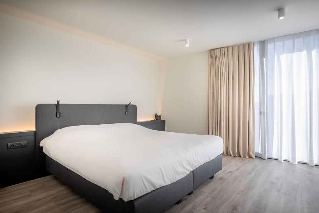 - une chambre avec un grand lit et une grande fenêtre dans l'établissement Hotel Bell-X Kortrijk-Wevelgem, à Wevelgem