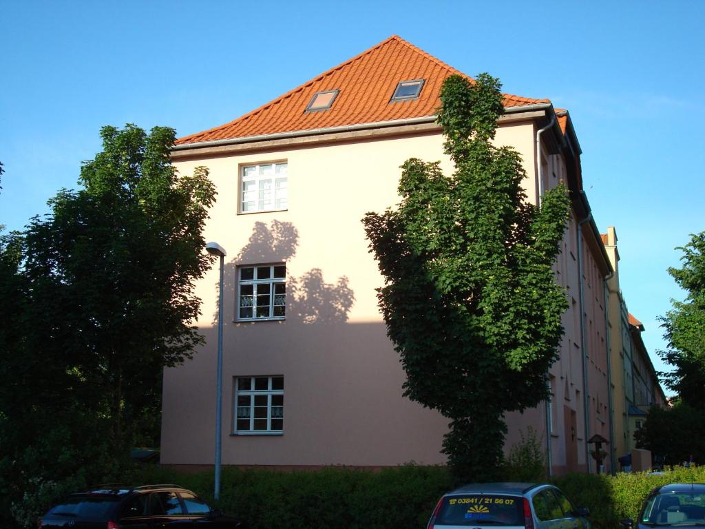 a white building with a tree in front of it at Fewo - Am Mühlenteich in Wismar