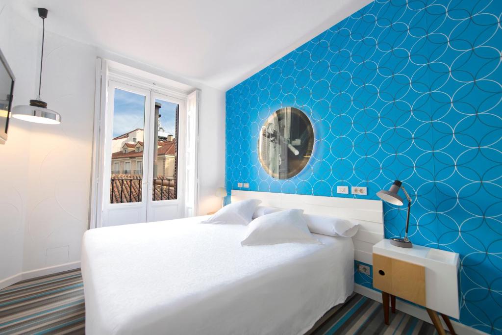 sypialnia z białym łóżkiem i niebieską ścianą w obiekcie Posada del Dragón Boutique Hotel w Madrycie