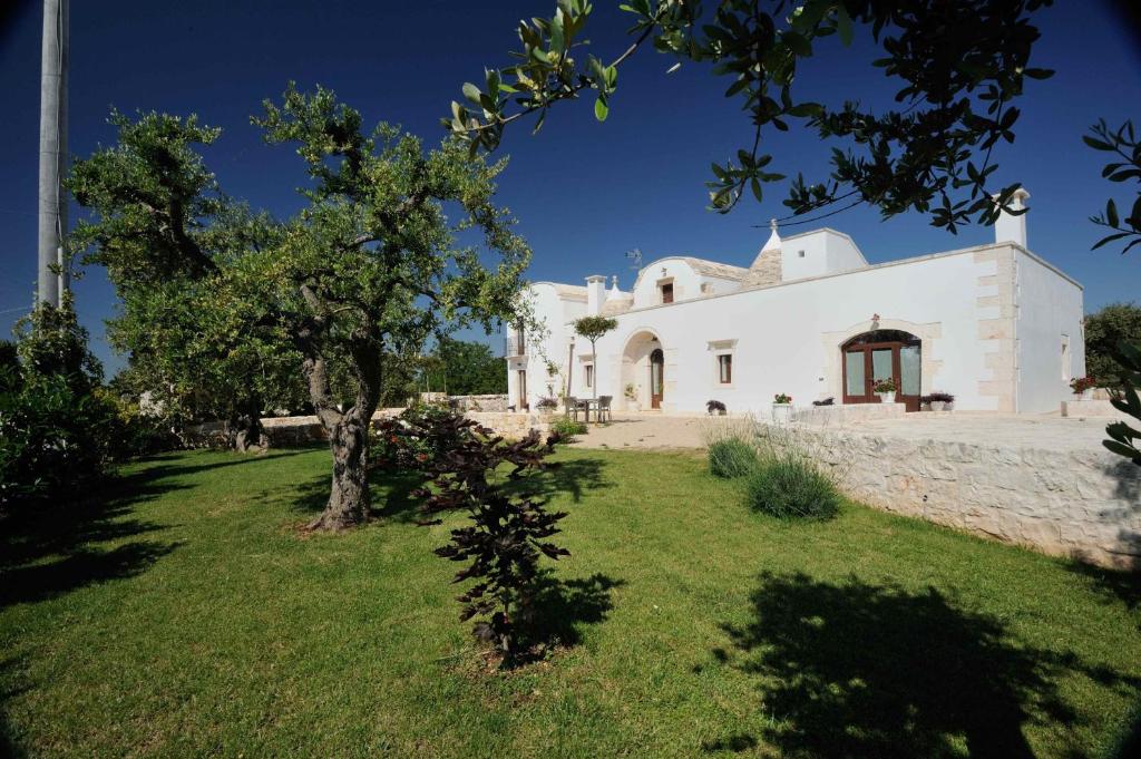 Una casa blanca con un árbol delante. en Agriturismo Arco di Sole, en Alberobello