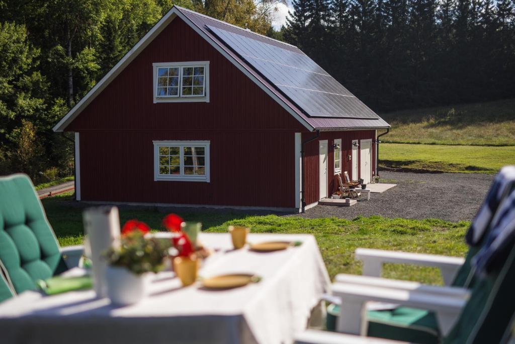 een rode schuur met een tafel en stoelen ervoor bij Solar Lake Cottage in Jönköping