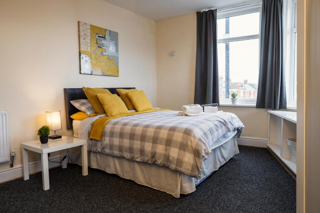 a bedroom with a bed with yellow pillows and a window at Dunes Hotel in Whitley Bay
