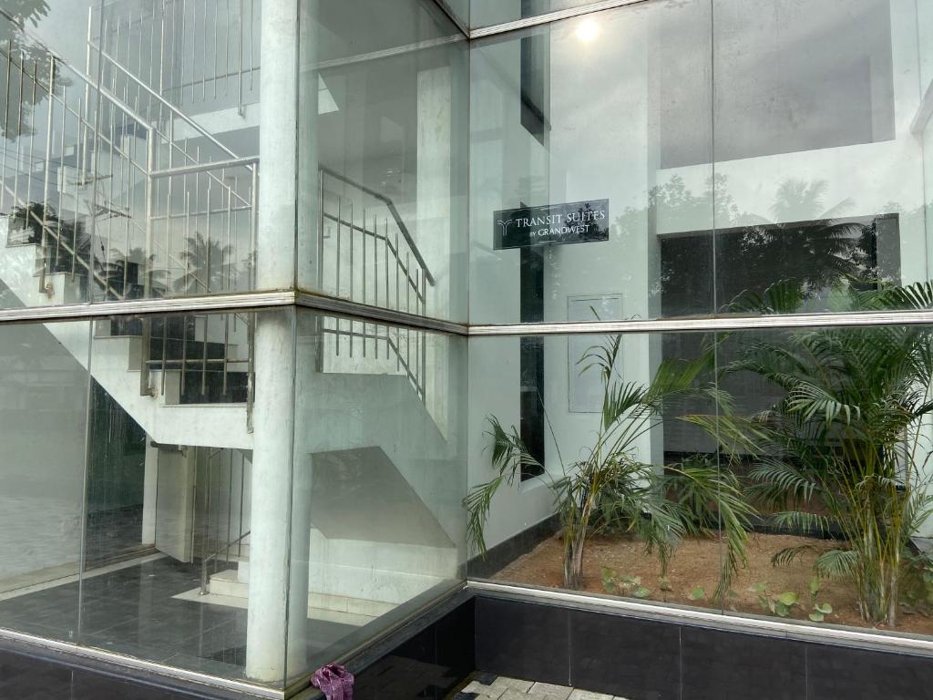 a reflection of a staircase in a glass building at Transit Suites by GrandWest in Nedumbassery