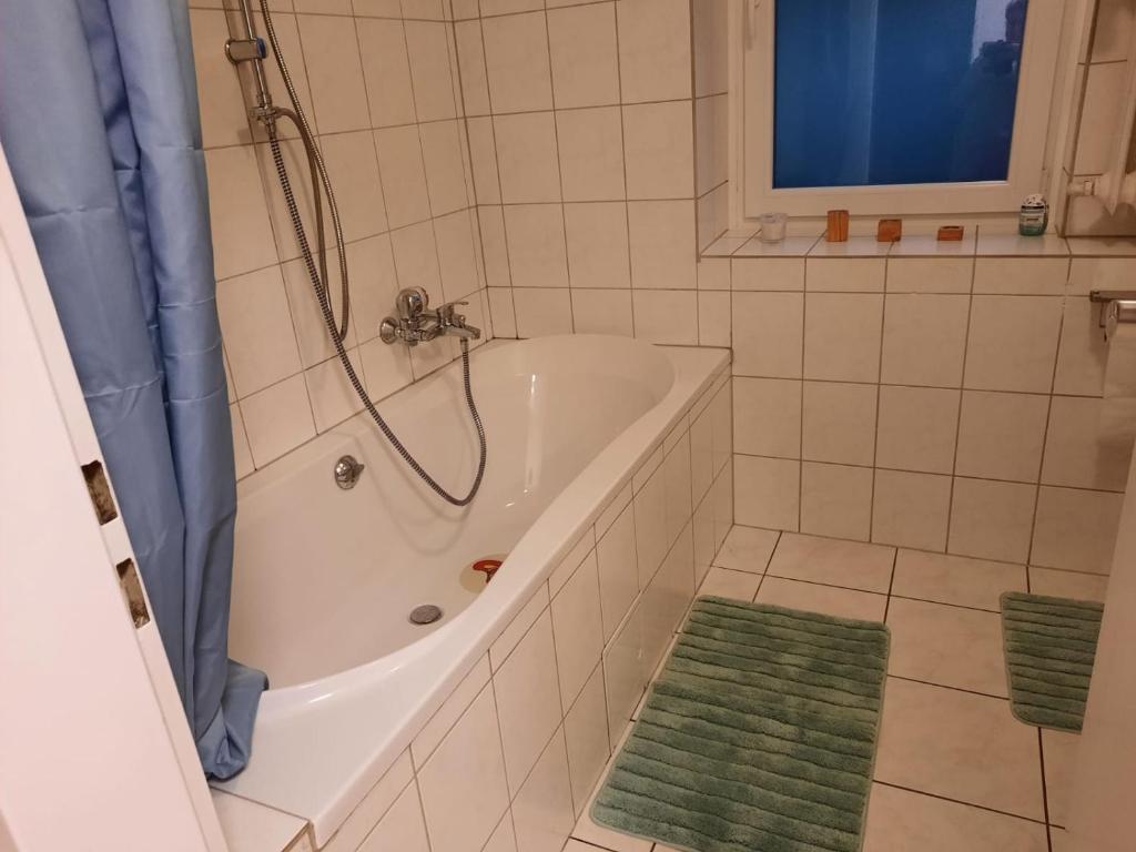 a bathroom with a tub and a green rug at Ferienwohnung Elena in Zweibrücken