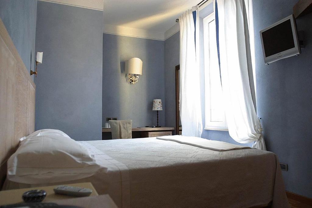 1 dormitorio con cama blanca y ventana en Albergo Morandi, en Reggio Emilia