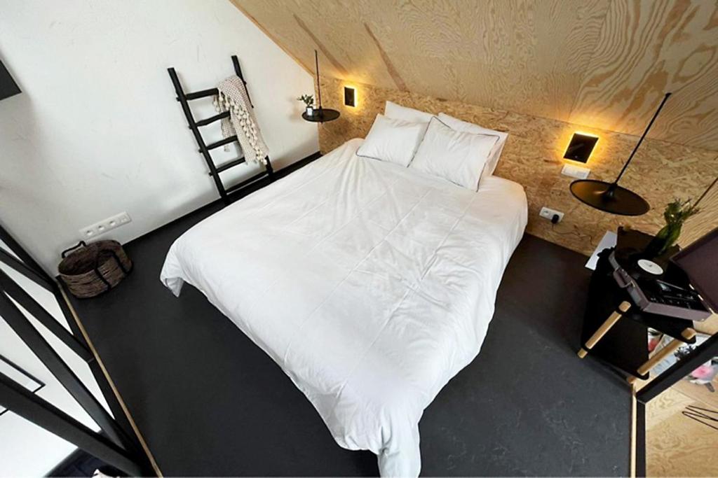 een slaapkamer met een groot bed met witte lakens bij Le Studio du Designer in Libin
