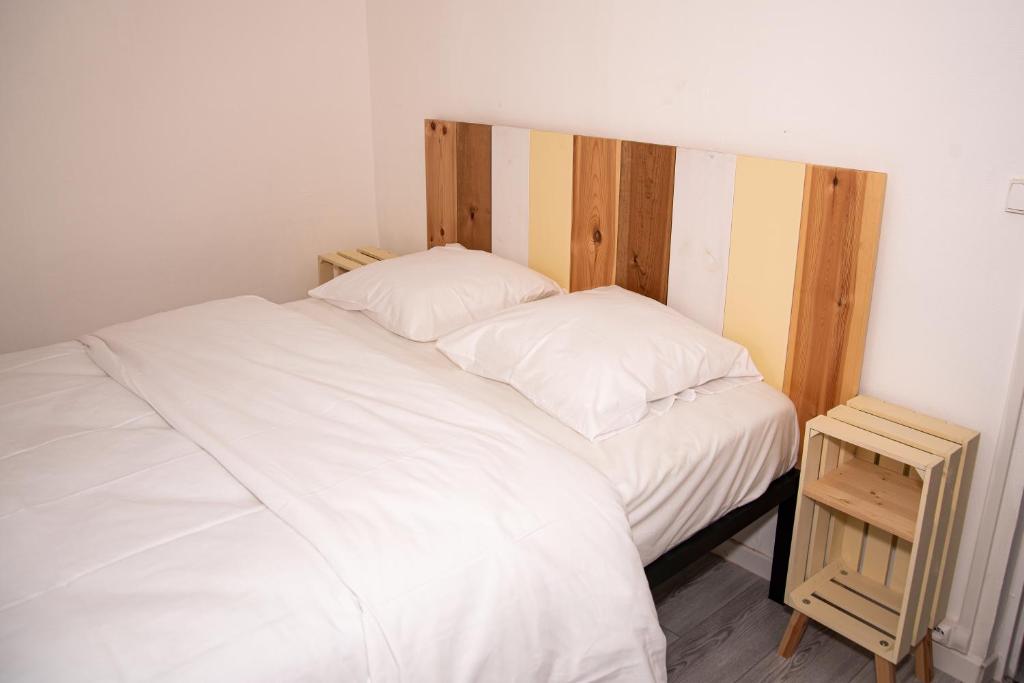 Cama blanca con cabecero de madera y mesita de noche en DG LOCATION en Saint-Quentin