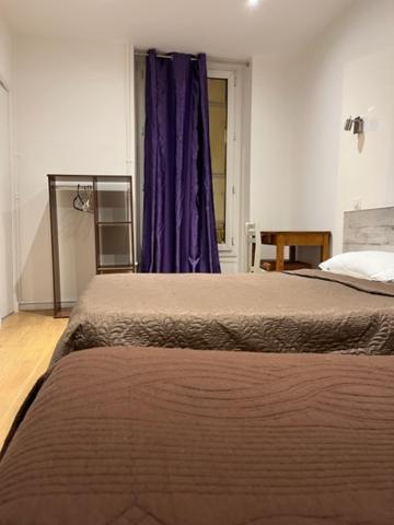 a bedroom with two beds and a purple curtain at Hotel Luna Park in Paris