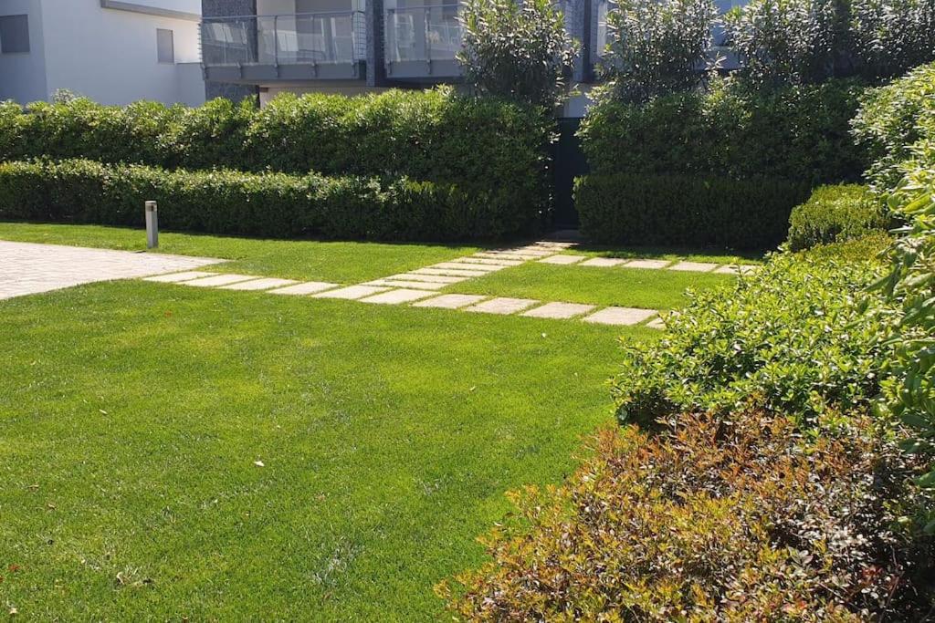 a yard with green grass and bushes and a building at Appartamento alle Dune! Dalla piscina alla spiaggia in 30 mt! in Silvi Marina