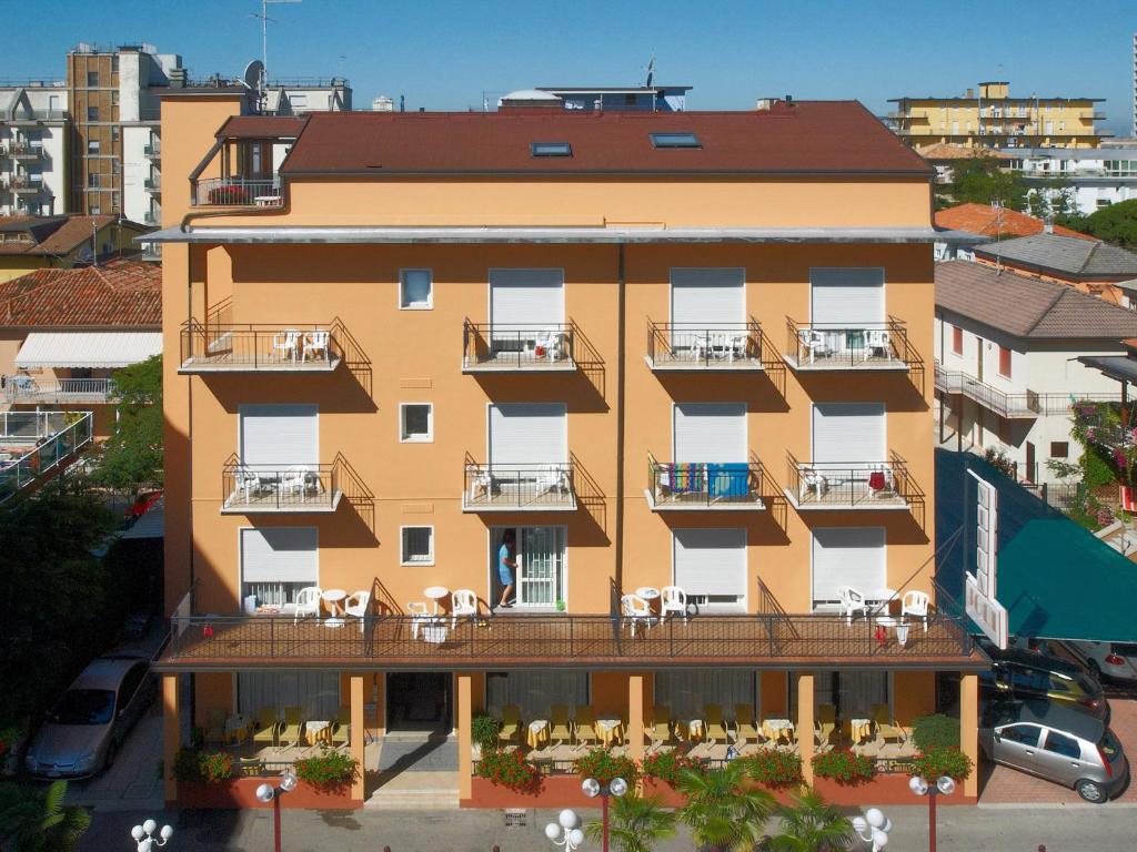 an apartment building with tables and chairs on the balcony at Pensione Villa Joli in Lido di Jesolo