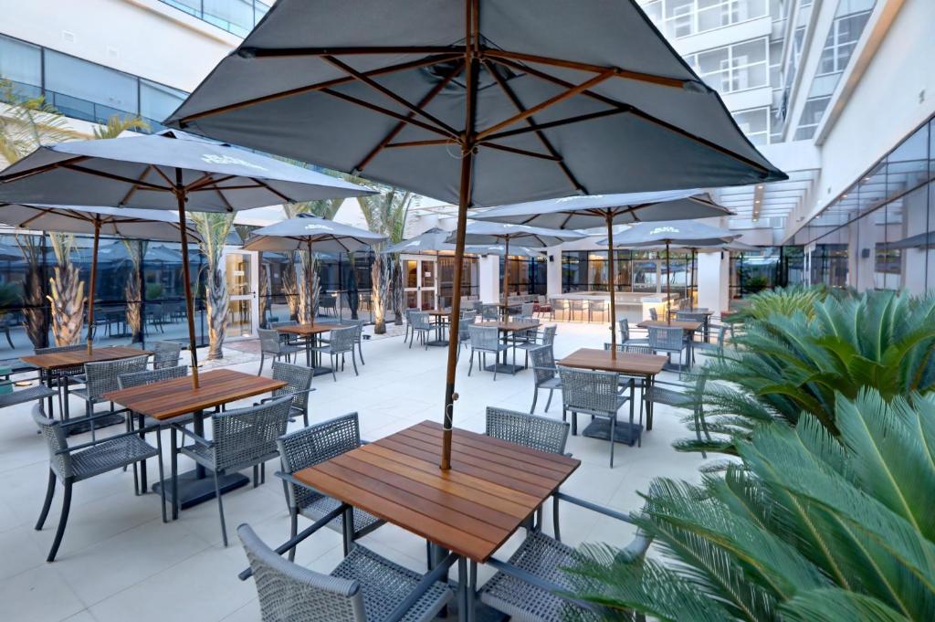 an outdoor patio with tables and chairs with umbrellas at Comfort Hotel Guarulhos Aeroporto in Guarulhos