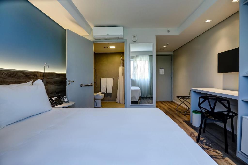 a bedroom with a large bed and a bathroom at Comfort Hotel Guarulhos Aeroporto in Guarulhos