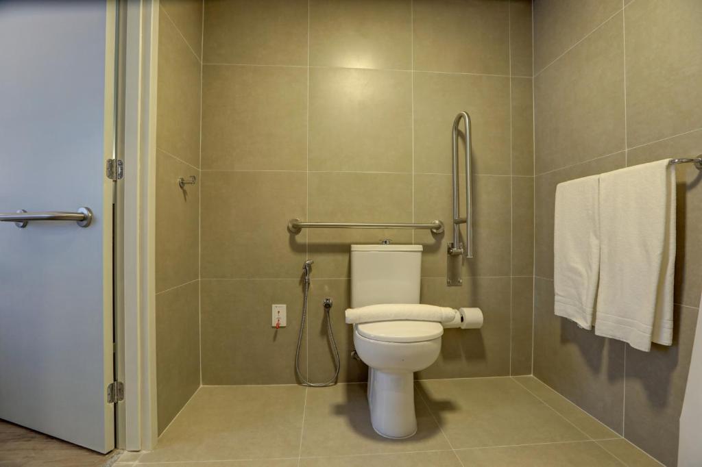 a bathroom with a toilet and a shower with towels at Comfort Hotel Guarulhos Aeroporto in Guarulhos