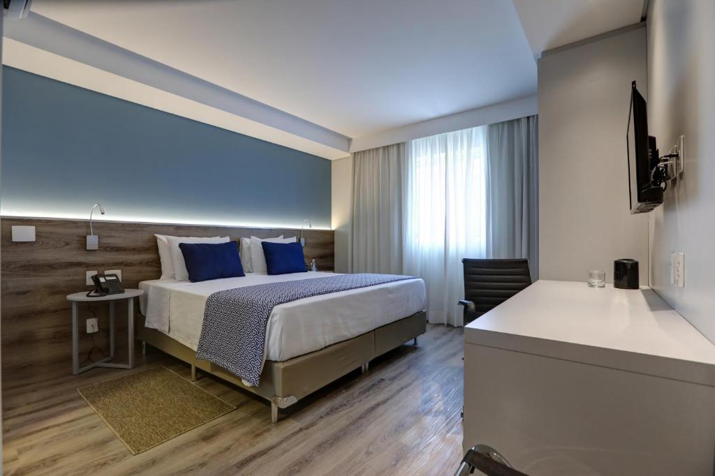 a bedroom with a bed with blue pillows at Comfort Hotel Guarulhos Aeroporto in Guarulhos