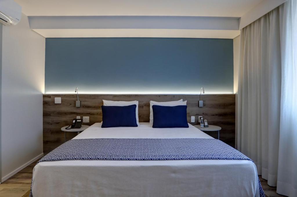 a bedroom with a large bed with blue pillows at Comfort Hotel Guarulhos Aeroporto in Guarulhos