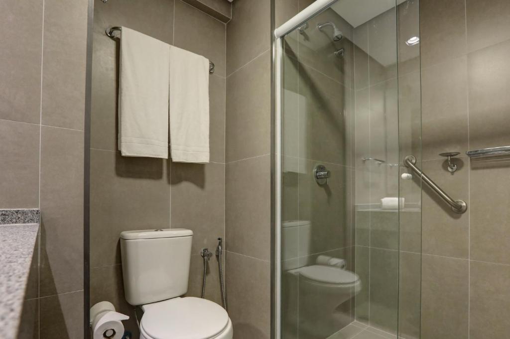 a bathroom with a toilet and a glass shower at Comfort Hotel Guarulhos Aeroporto in Guarulhos