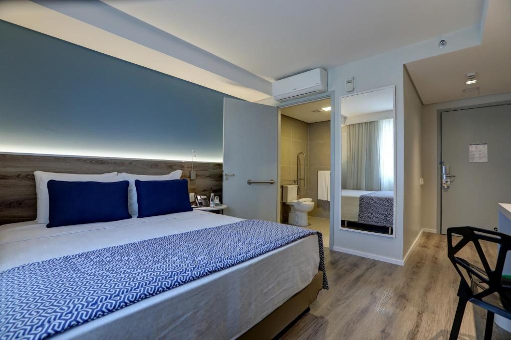 a bedroom with a large bed with blue pillows at Comfort Hotel Guarulhos Aeroporto in Guarulhos