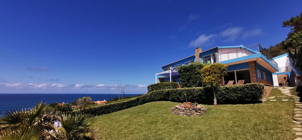 uma casa numa colina com o oceano ao fundo em Mega Ocean Magoito - Guest House - Sintra em Sintra