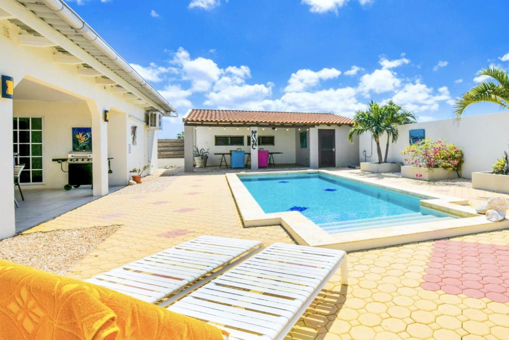 a backyard with a swimming pool and a house at Sunny Palm Beach Villa in Palm-Eagle Beach